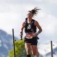 Liciane Braun correndo em uma trilha com montanhas ao fundo